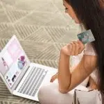 Young woman shopping online with credit card and laptop at home