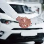 Poignée de mains devant une voiture