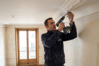 Technicien installant une alarme dans un appartement haussmannien avec moulures en stuc
