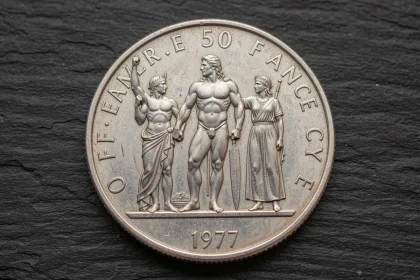 Gros plan macro d'une pièce authentique en argent 50 Francs 1977 montrant les détails du relief Hercule sur fond ardoise sombre